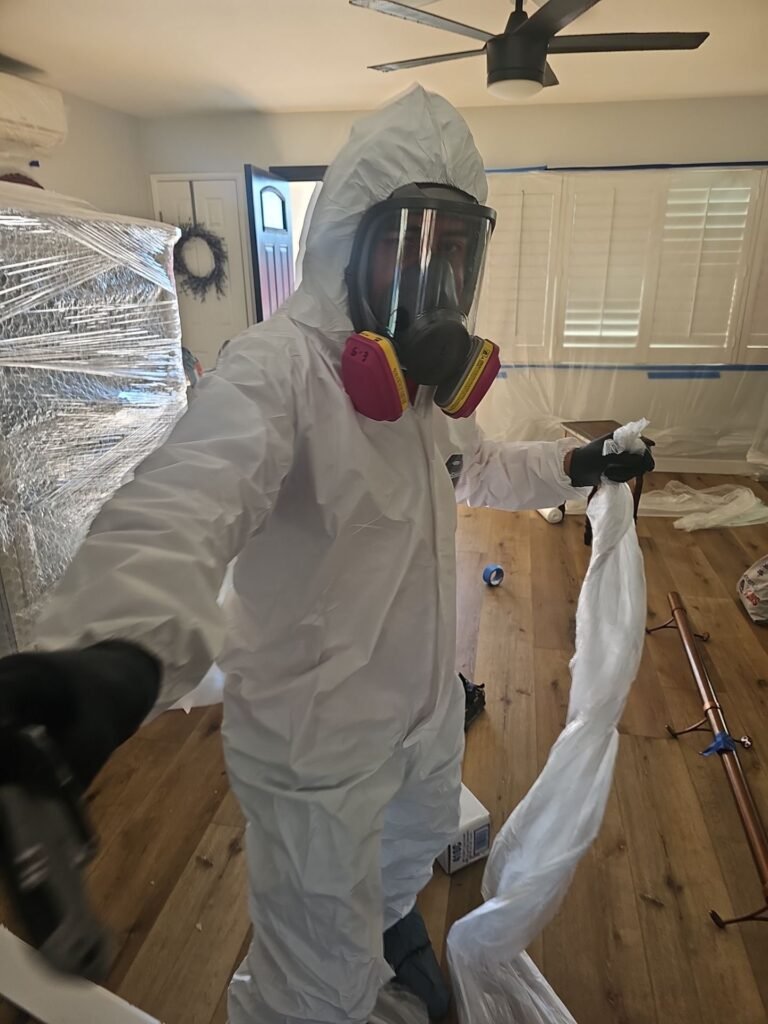 Technician in full protective gear sealing containment plastic during a mold remediation in Santa Ana