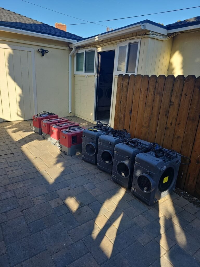 Dehumidifiers and air scrubbers staged in a Santa Ana driveway at the start of a drying job