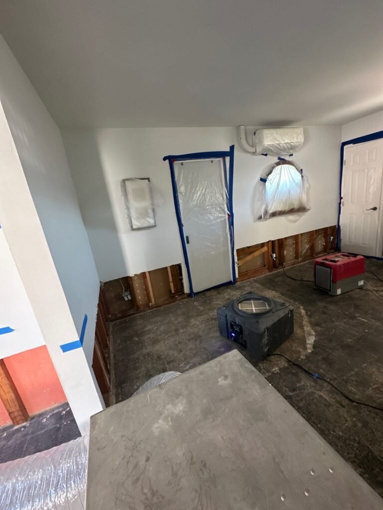 Baseboards removed and the wall cavity opened to dry a Santa Ana living room