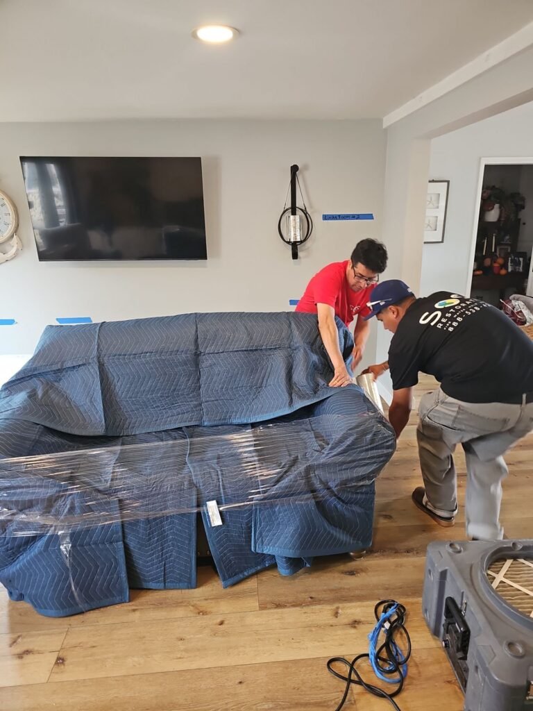 SOS Restoration technicians wrapping a sofa before drying begins in a Santa Ana home