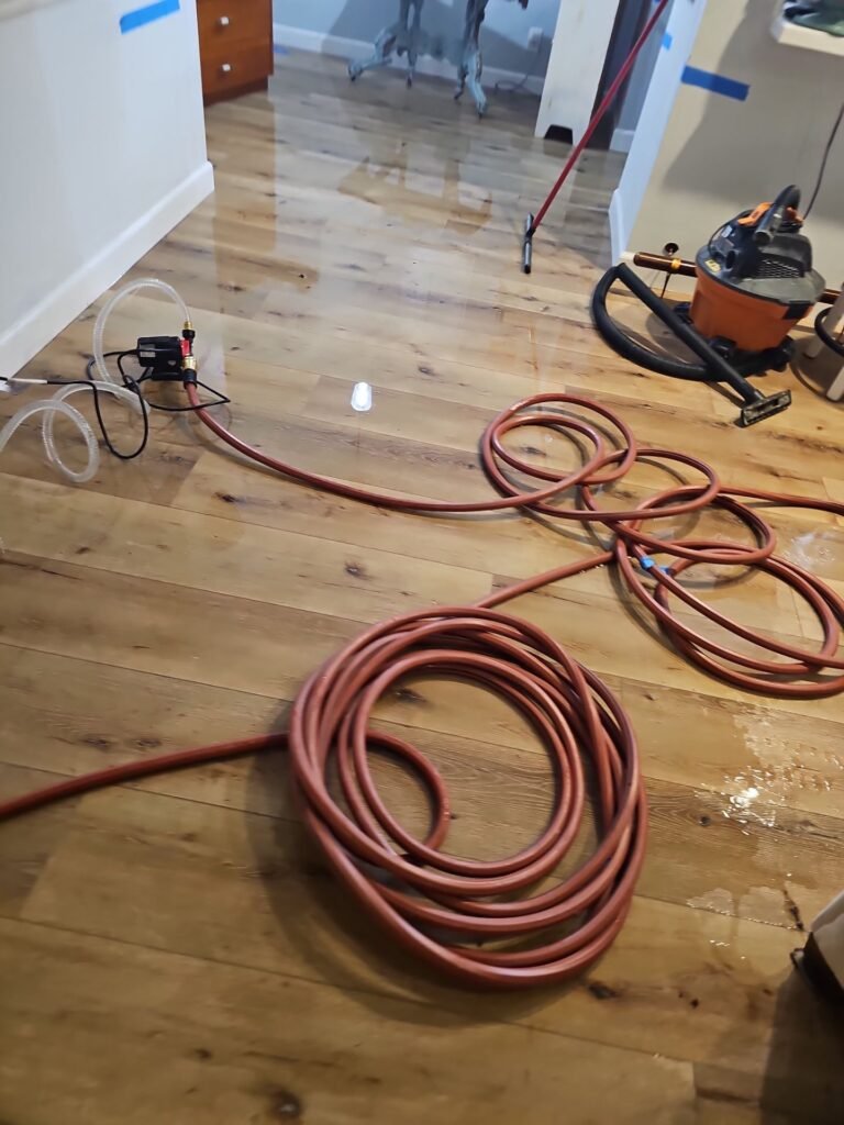 Extraction hose run across a hardwood floor in a Santa Ana home