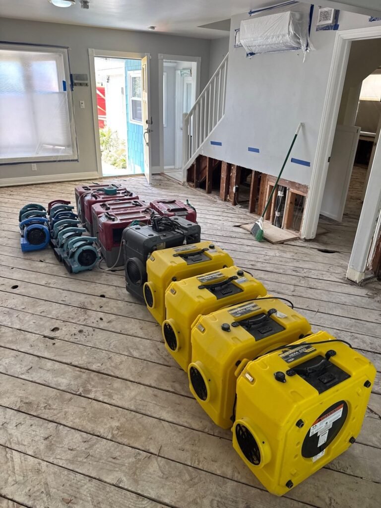 Air movers lined up along an opened wall in a Santa Ana home