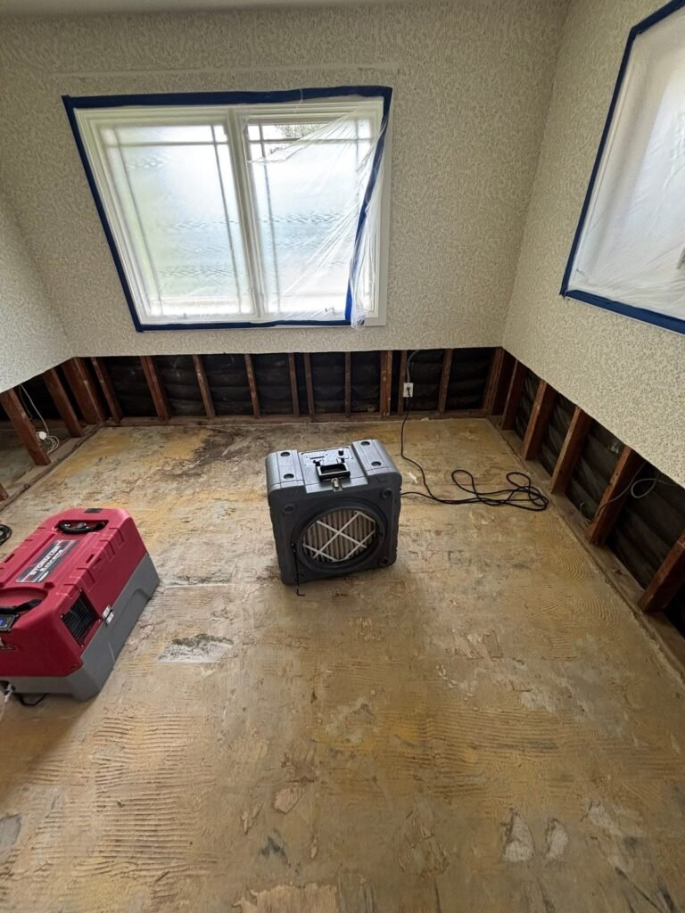 A small room cut at the base with a red dehumidifier and a black air scrubber in Santa Ana