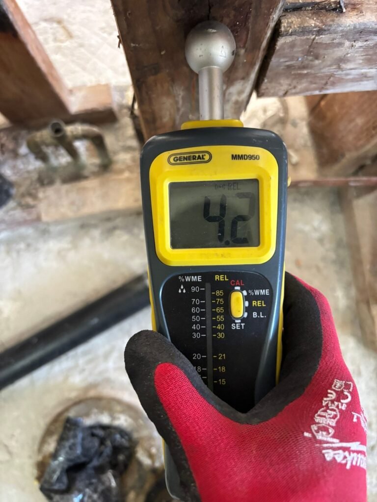 A moisture meter reading 42 against a wooden beam in Santa Ana