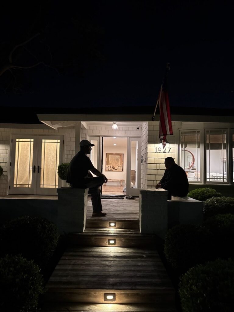 Two technicians at the lit entry of a house at night in Santa Ana