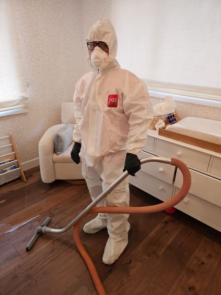 A suited technician running an extraction hose through a furnished bedroom in Santa Ana