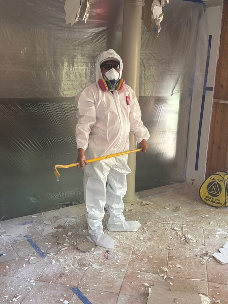 A technician holding a pry bar inside containment with debris underfoot in Santa Ana