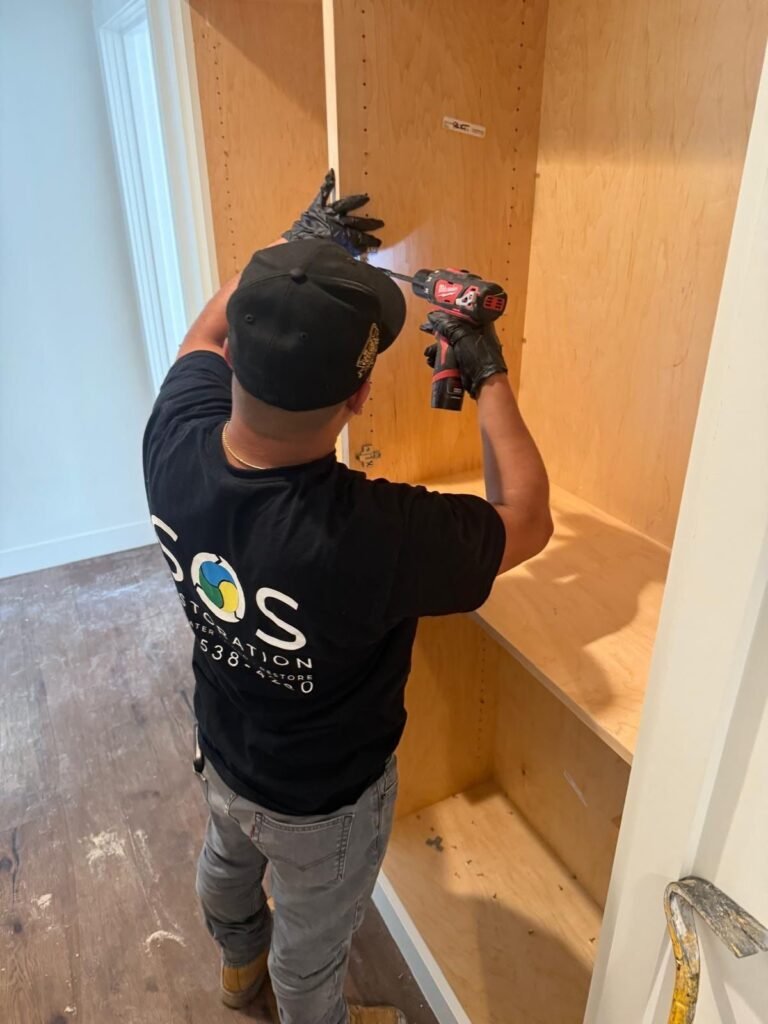 An SOS technician driving screws inside a wooden cabinet during the rebuild in Santa Ana
