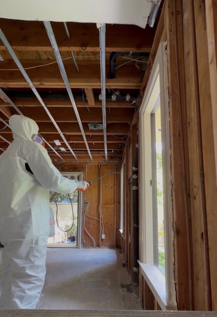A technician beside a window in a room opened to the ceiling joists in Santa Ana