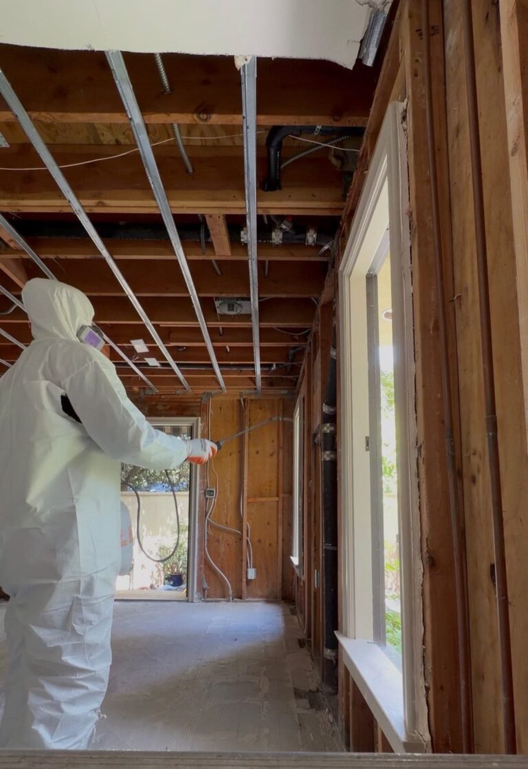 A technician beside a window in a room opened to the ceiling joists in Santa Ana
