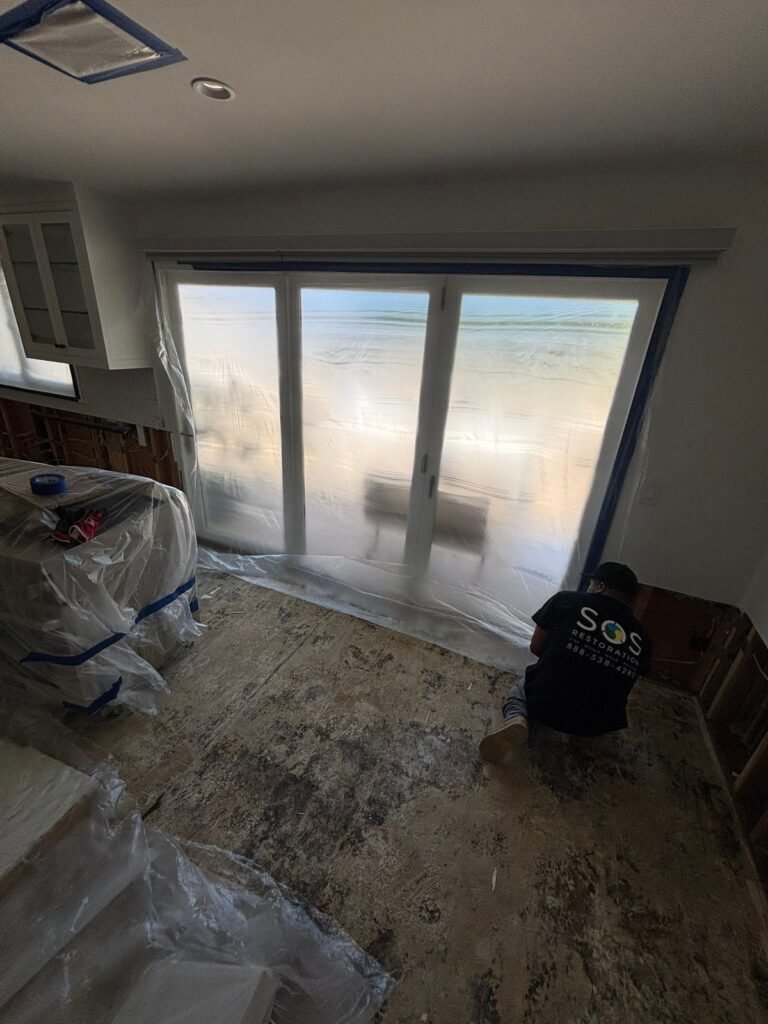 Containment plastic beside a wall of windows with the floor stripped bare in Santa Ana